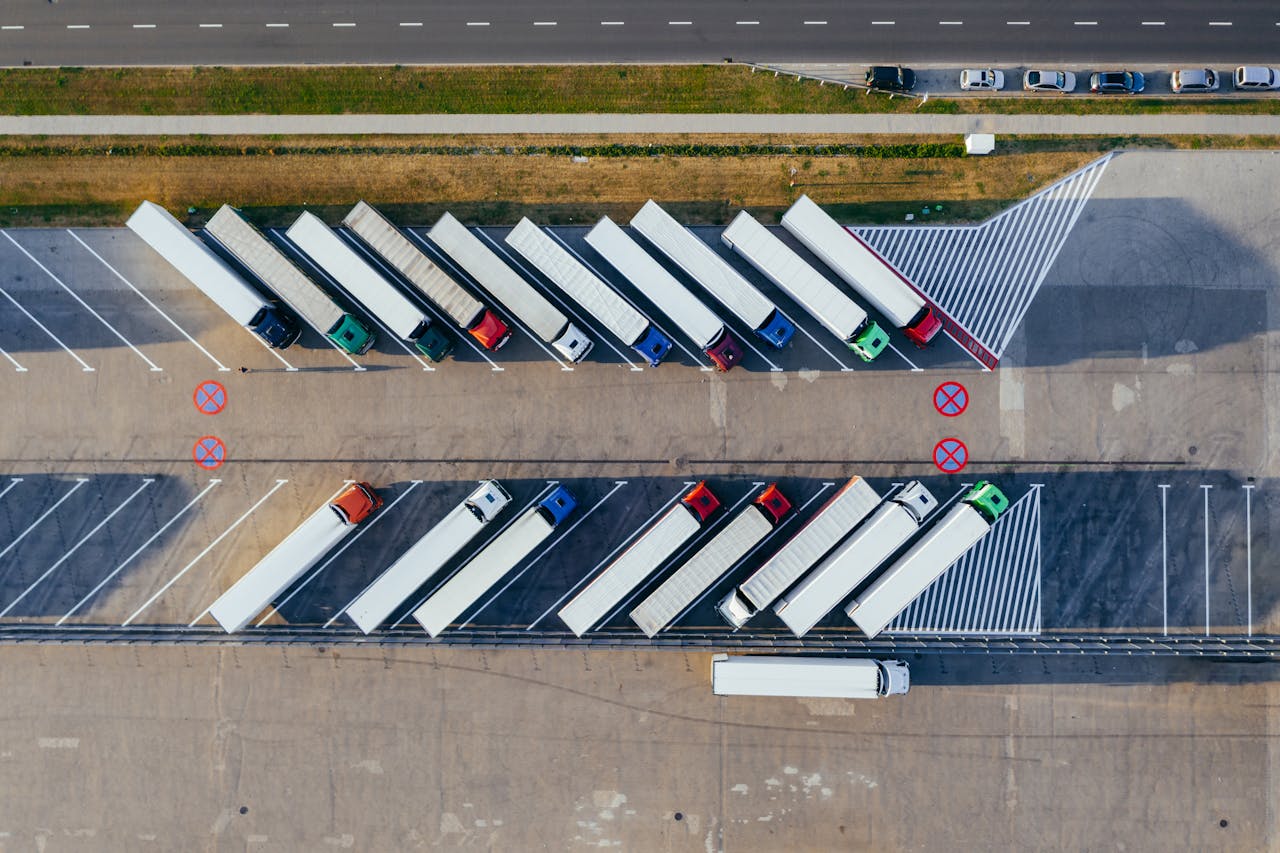 footer-cta-img Overhead shot of semi-trucks parked in PoznaĆ, Poland, demonstrating transportation logistics.