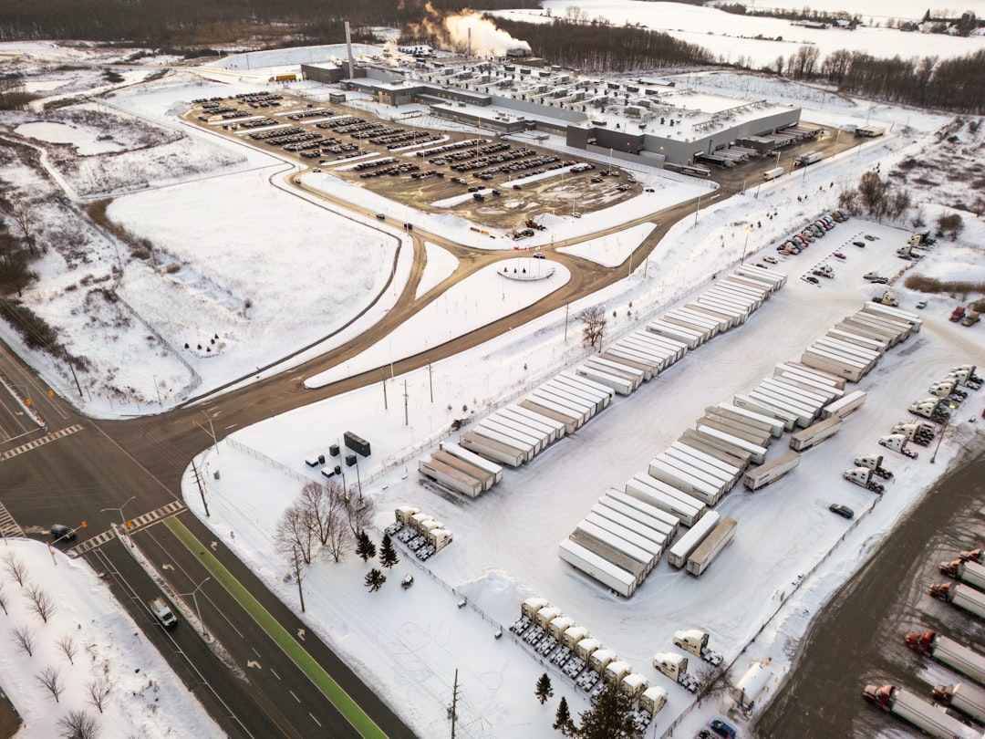 aerial-view-of-a-snowy-industrial-complex-with-trucks-j9nsvrvkfeq